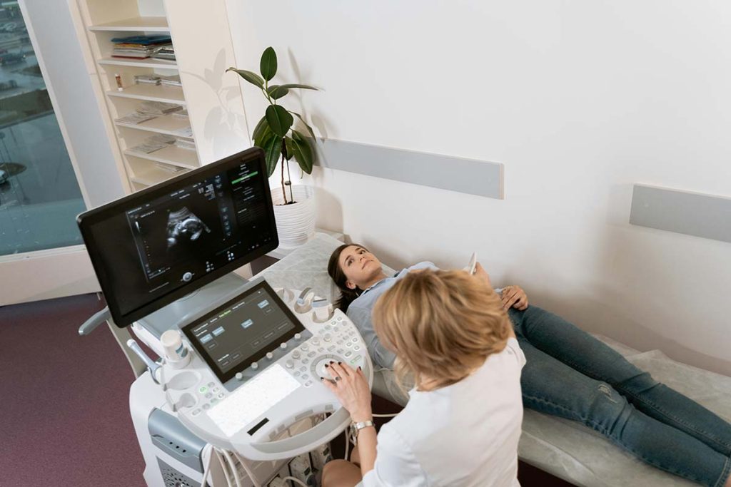 Obstetrician performing 9‑month pregnancy growth scan on woman in UK clinic